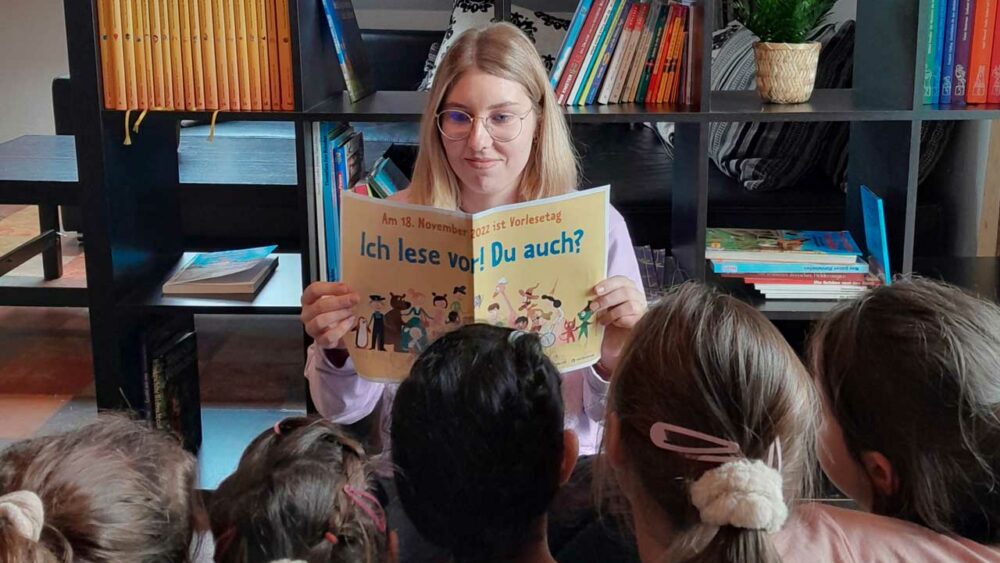 Vorlesetag: Frau liest Kindern etwas vor.