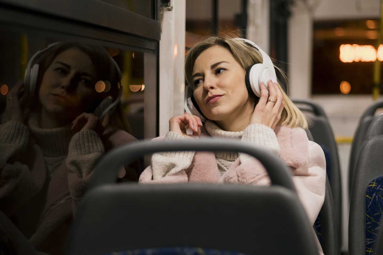 Frau entspant mit Kopfhörern im Bus